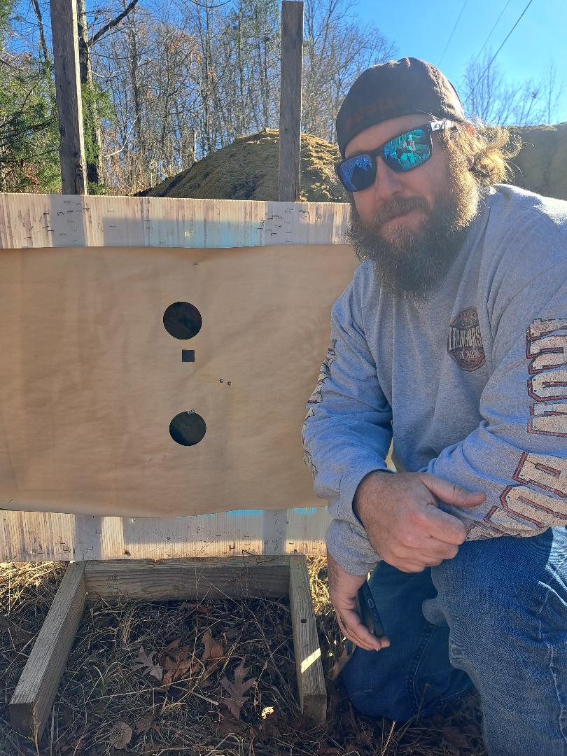 A young man kneeling beside his paper target at Lewis Creek’s rifle range